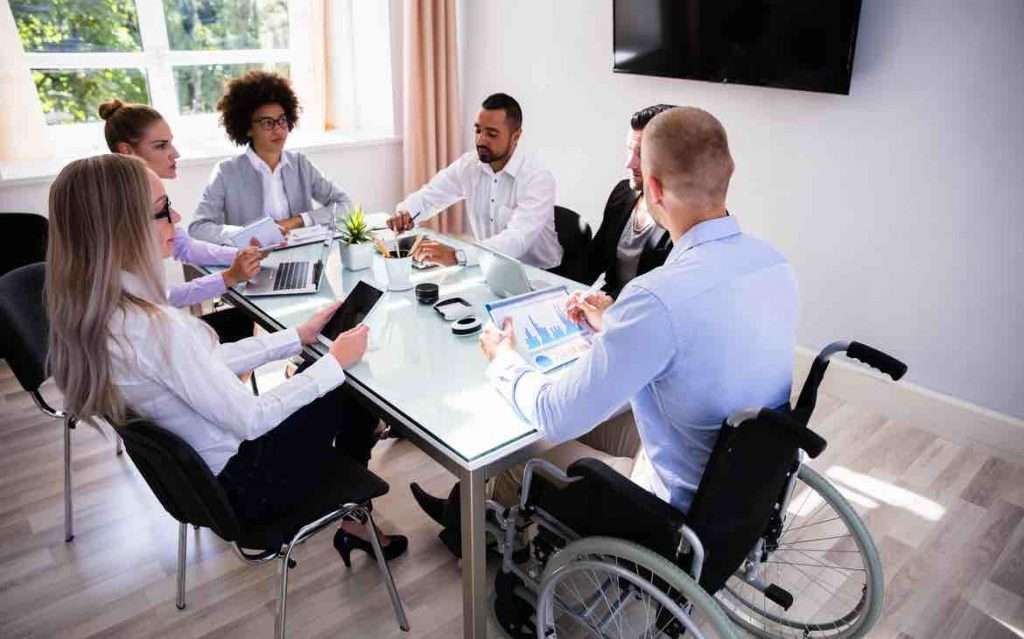 Disabled male in a wheelchair meeting with his colleagues at a table