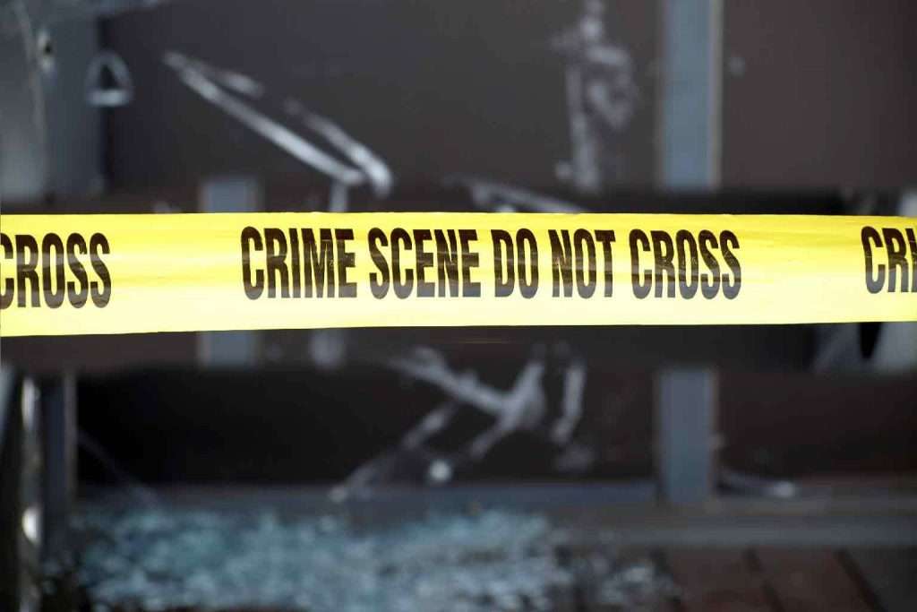 Yellow tape blocks off a crime scene with broken glass