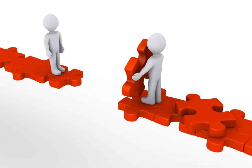 Two 3d figures attempting to bridge a gap using jigsaw pieces